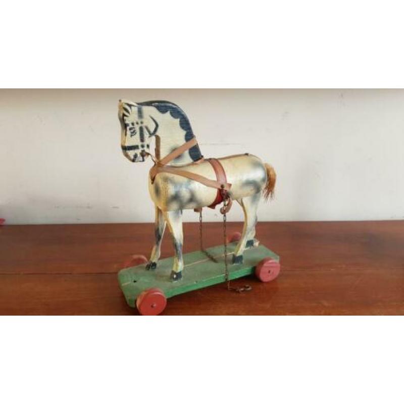 Antiek paard op plankje met wieltjes
