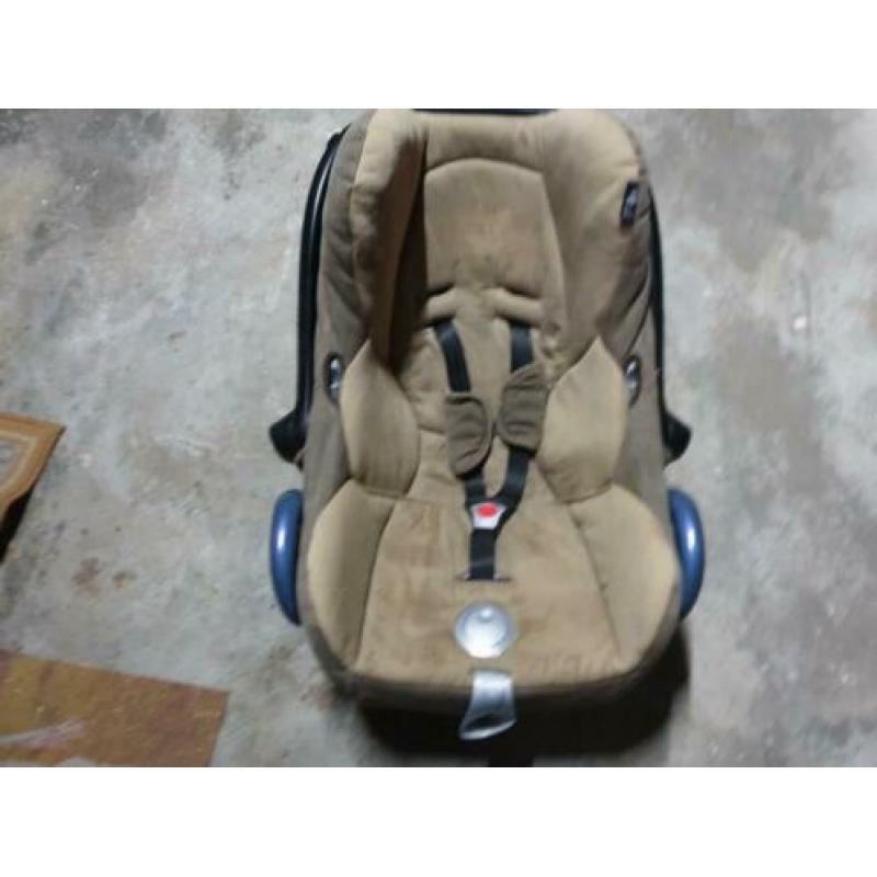 Blauwe maxi cosi met bruine binnenhoes en blauwe hemel.